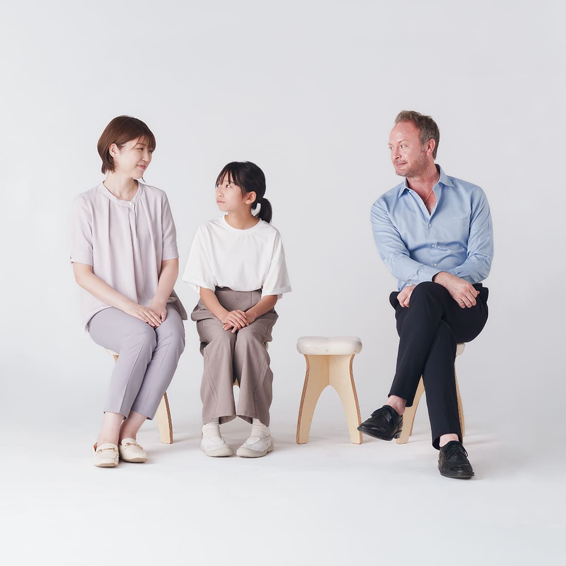 Three people seated on STOOTH stools